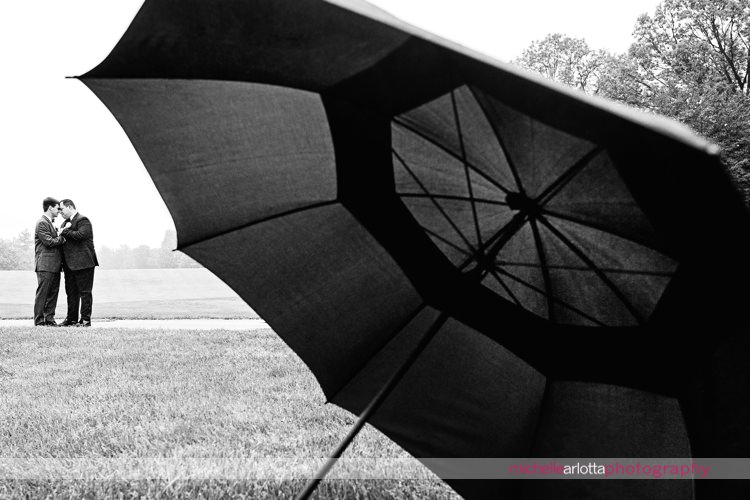 two grooms with umbrella in the foreground at denville nj country club wedding