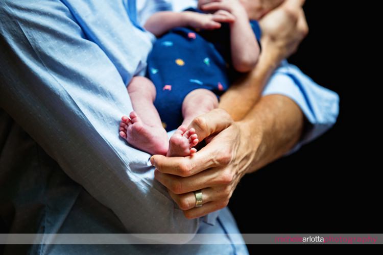 father holds his newborn son's feet