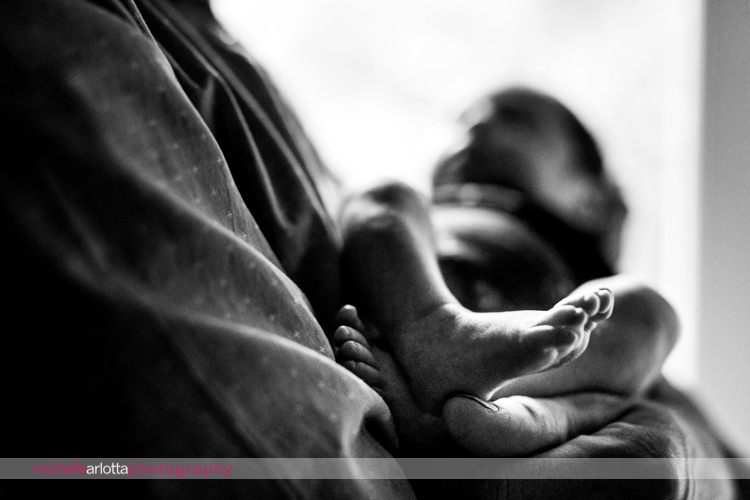 father holds his daughter's feet in her hands