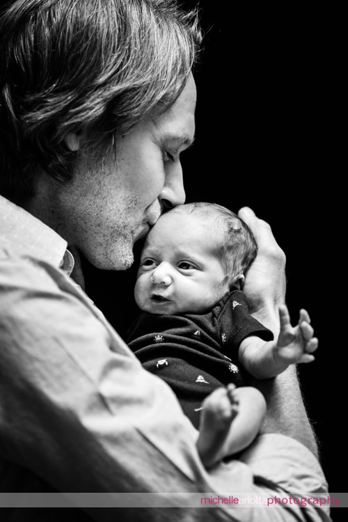 father kisses his newborn son's head newborn photography nj