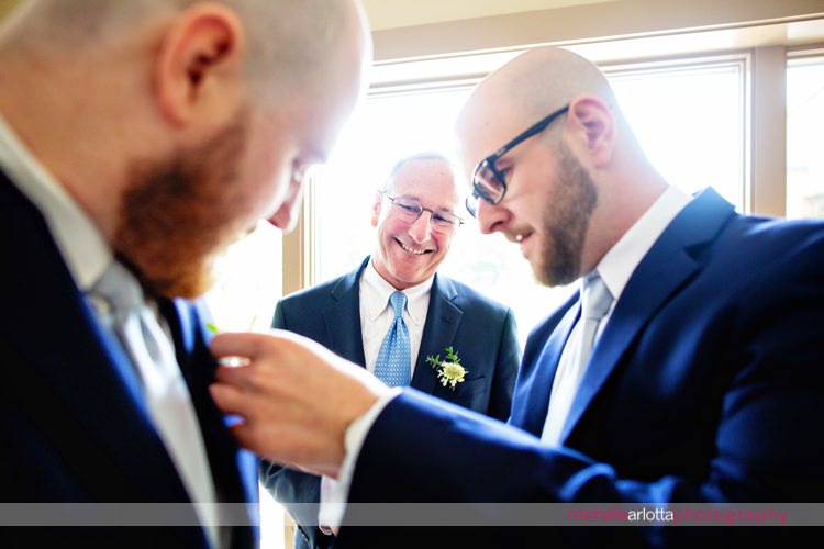 father of the grooms watches his two sons help each other during groom prep at rock island lake club