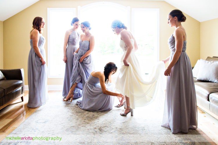 bridesmaids in weddington way dresses help bride in Sarah seven wedding dress put on shoes