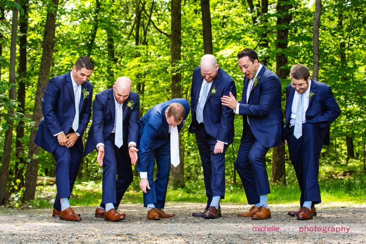 groomsmen in blue suits hike up their pants to show off their blue socks at New Jersey wedding