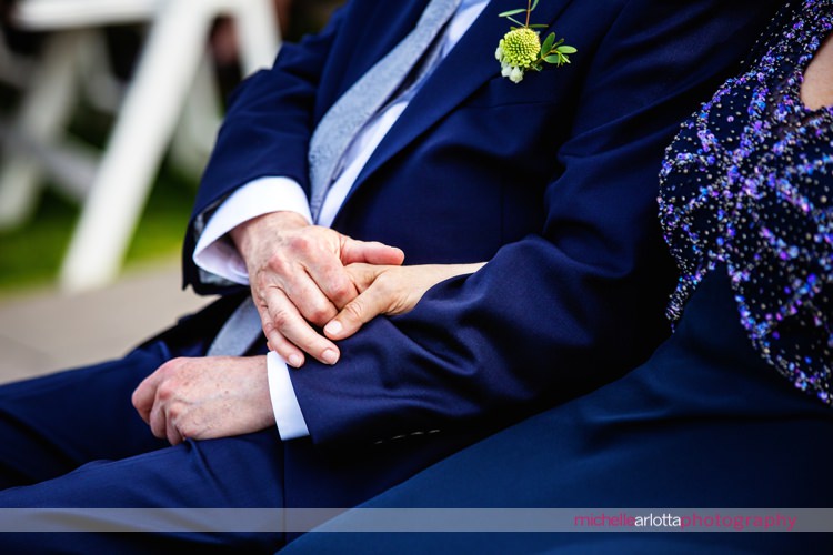 parents of the bride hold hands during nj wedding ceremony