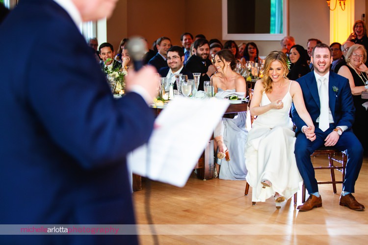 bride and groom laugh during father's toast at lakeside Sparta New Jersey wedding venue