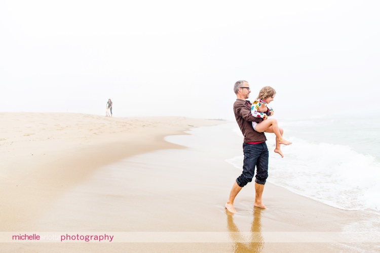 father and daughter play in the water in nj on a foggy day