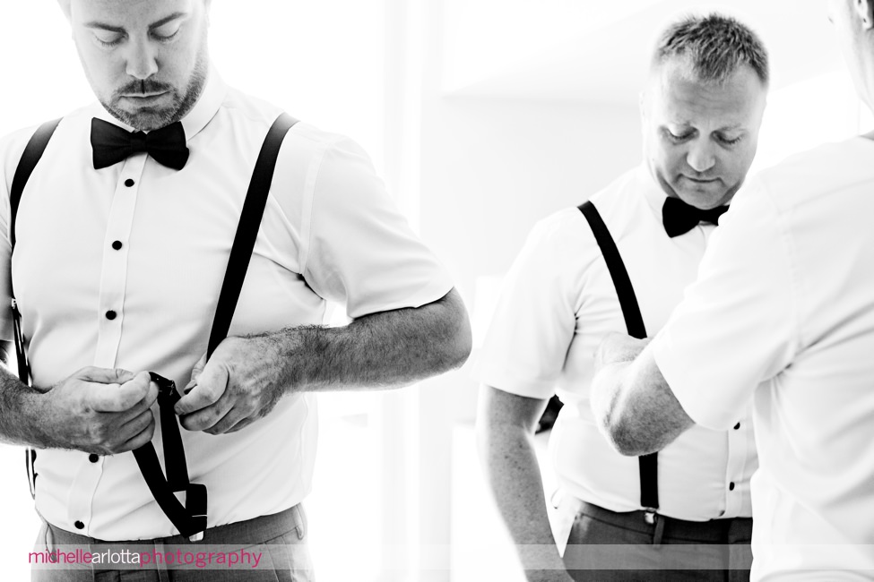 groom in blue bowtie and and blue suspenders gets ready at grand hotel in cape may nj