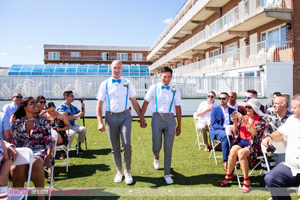 two grooms walk down the aisle together at start of rooftop cape may wedding ceremony
