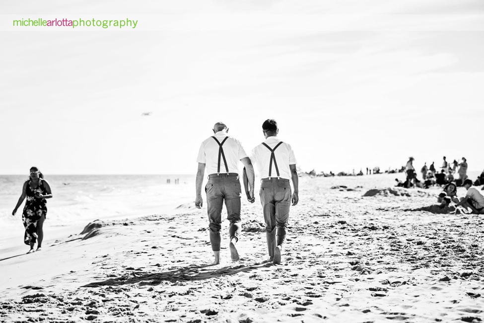 two grooms in blue bowties and blue suspenders smile together for portraits on the beach for their same sex grand hotel cape may wedding photographed by lgqbm friendly photographer Michelle arlotta