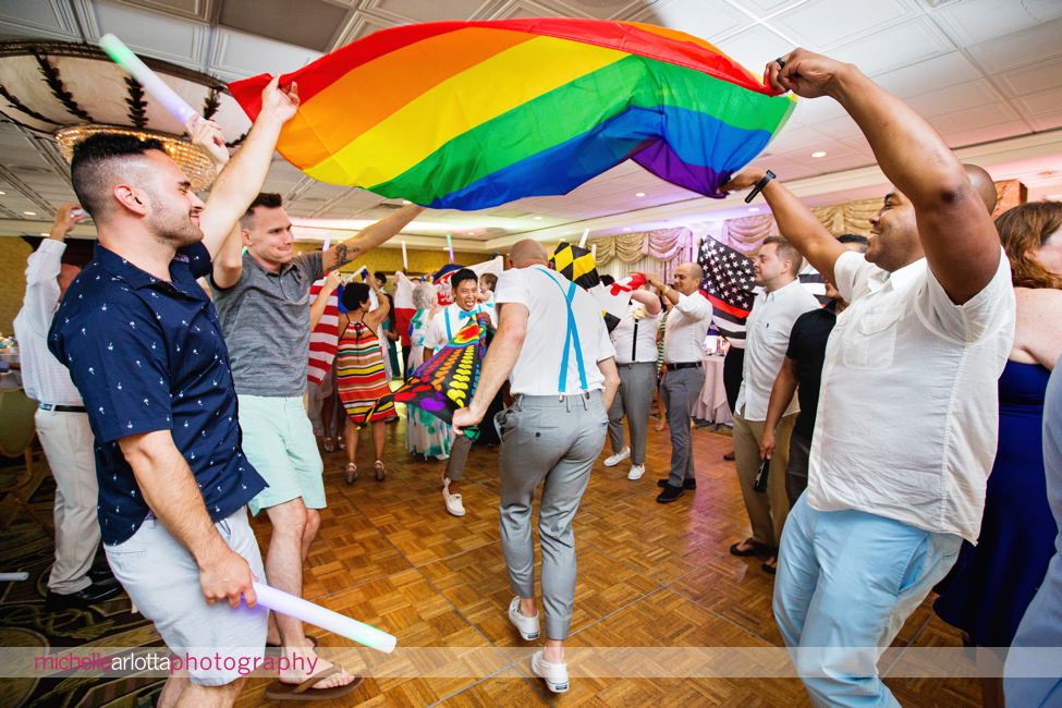two grooms dance under rainbow flag during united flag dance at their grand hotel reception in New Jersey