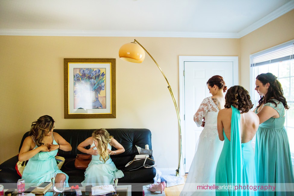 bridesmaids in shades of mint adjust boobs while bride gets in dress