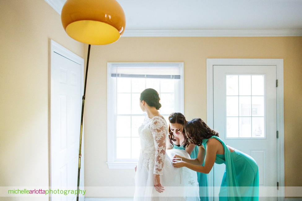 bridesmaids in shades of mint help bride gets in dress