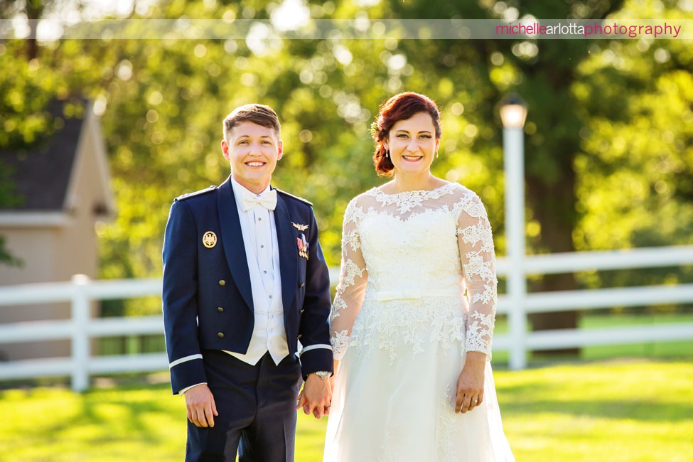 New Jersey bride in lacy dress with groom in Air Force uniform in paddocks at their landmark venues ryland inn