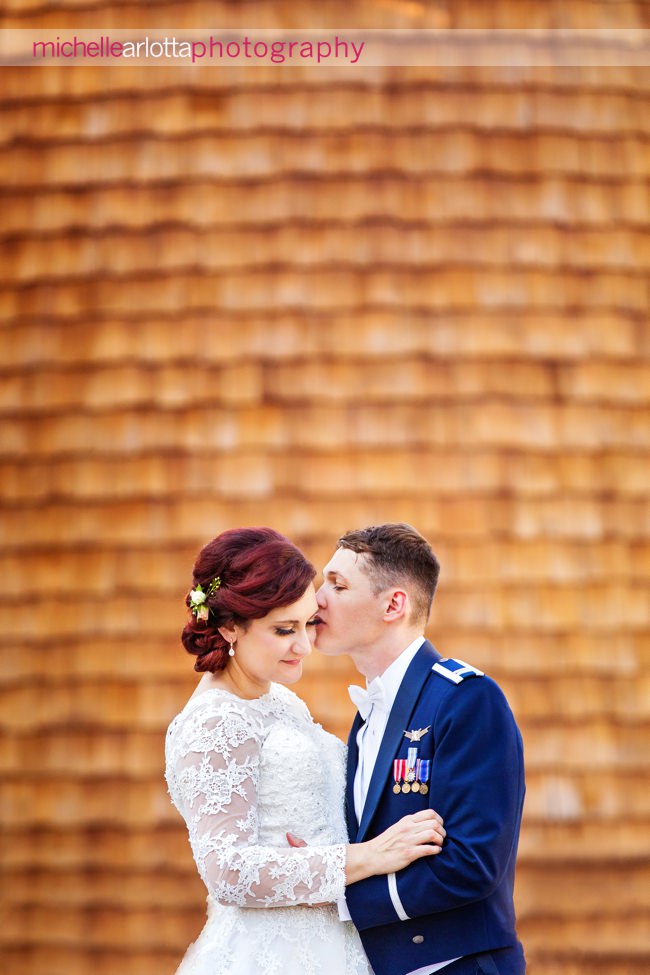 New Jersey bride in lacy dress with groom in Air Force uniform in front coach house silo at their ryland inn coach house summer wedding