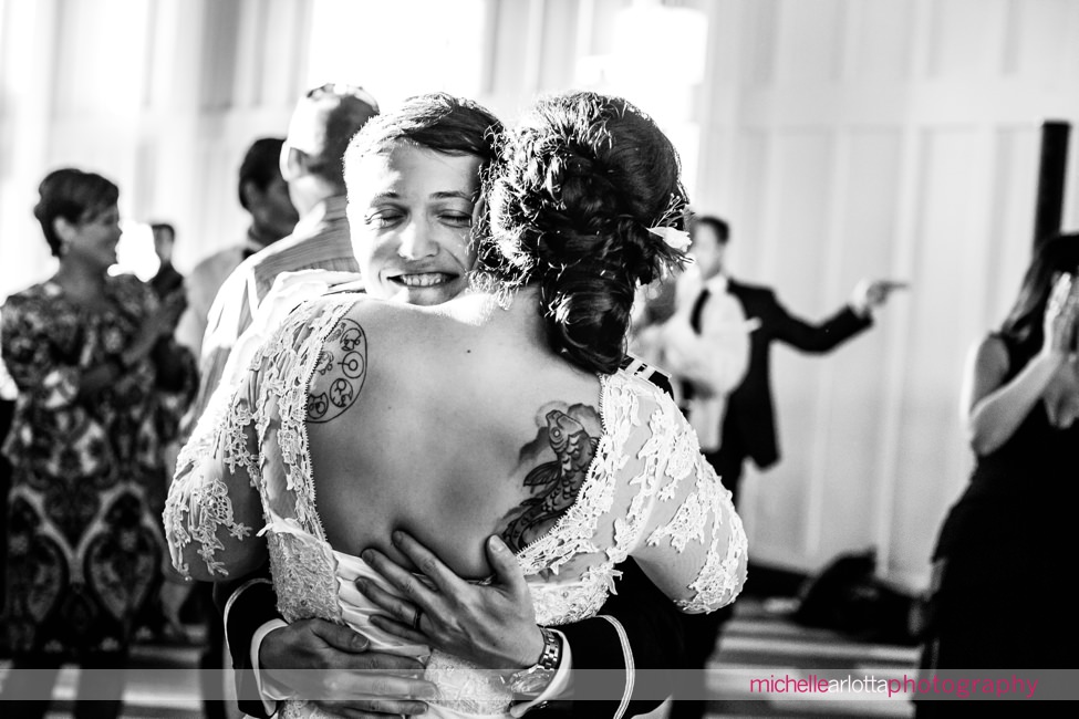 groom hugs bride in lacy wedding dress at their summer wedding reception at the ryland inn coach house in New Jersey