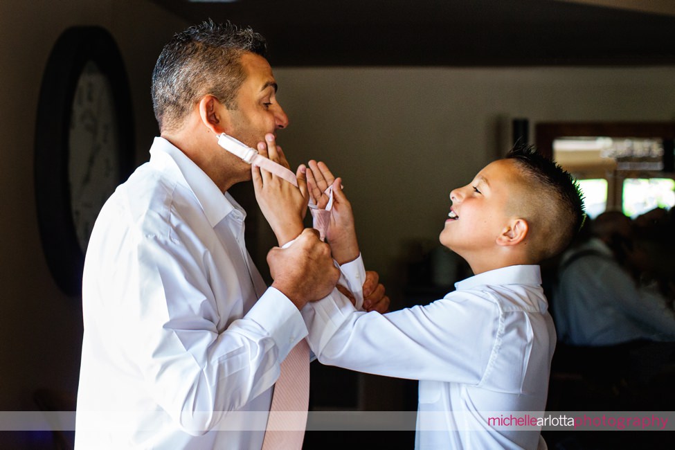 ring bearer helps his dad with his tie in woodford lounge bear brook groom prep