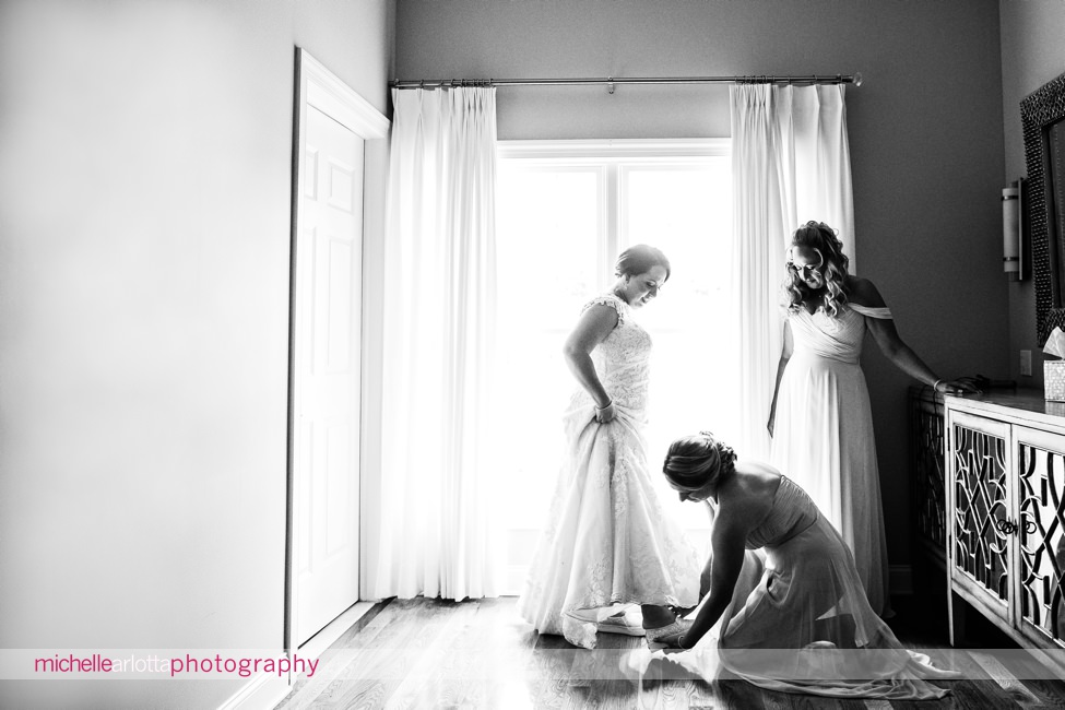 bride gets help from bridesmaid with her wedding keds at bear brook valley sunny summer wedding