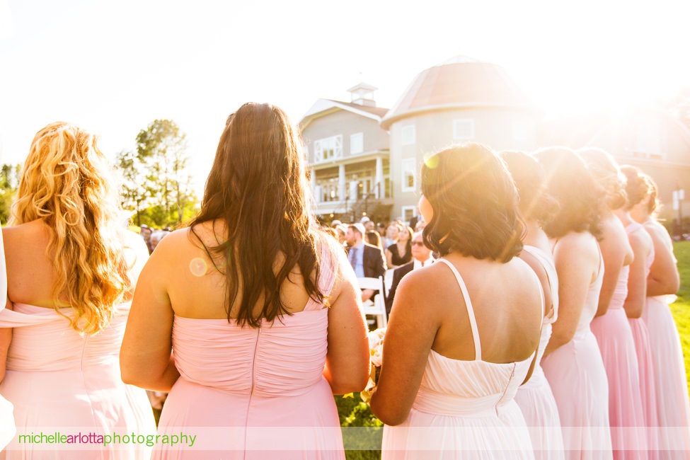 bridesmaids in pink dresses look on as bride heads down the aisle at New Jersey bear brook valley sunny summer wedding outdoor jewish ceremony captured by award winning New Jersey photographer Michelle arlotta