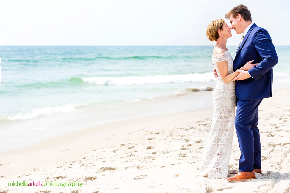 bride in bhldn and groom walk on beach during lbi gables inn intimate wedding New Jersey