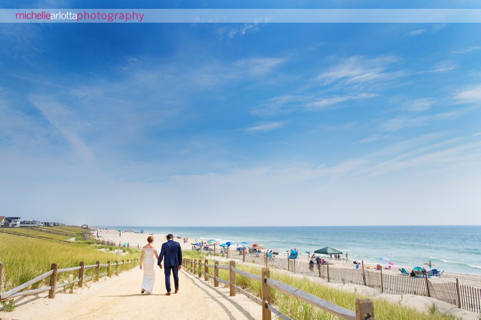 bride in bhldn and groom walk on beach during lbi gables inn intimate wedding New Jersey