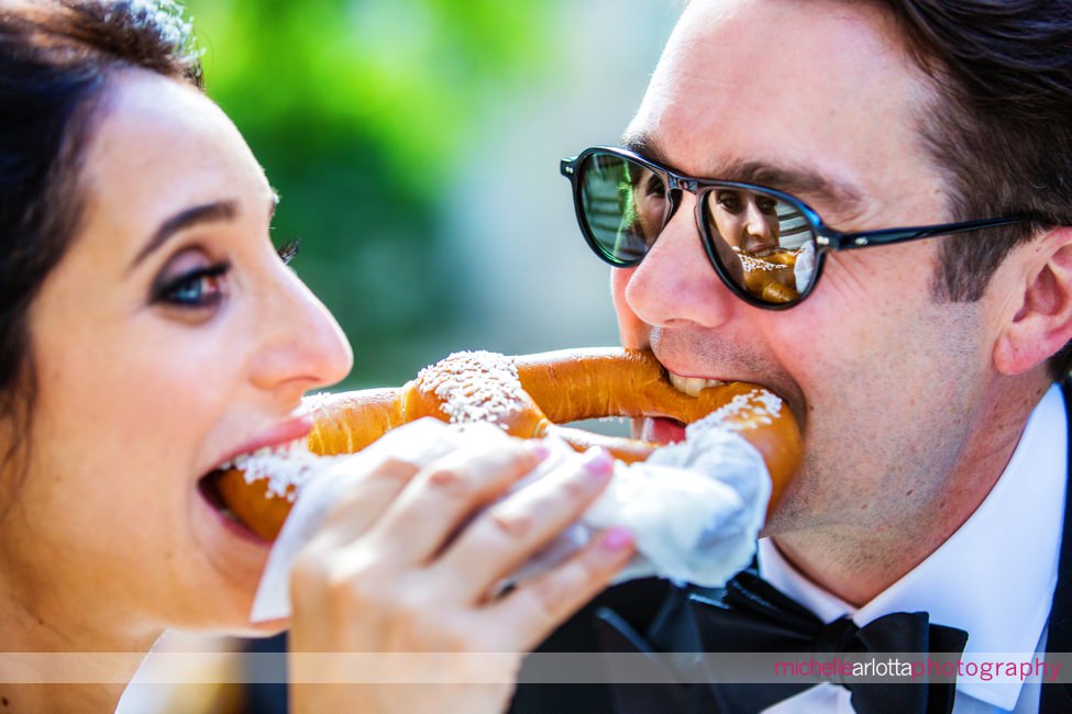 Liberty House summer wedding new jersey couple biting nyc pretzel at the same time