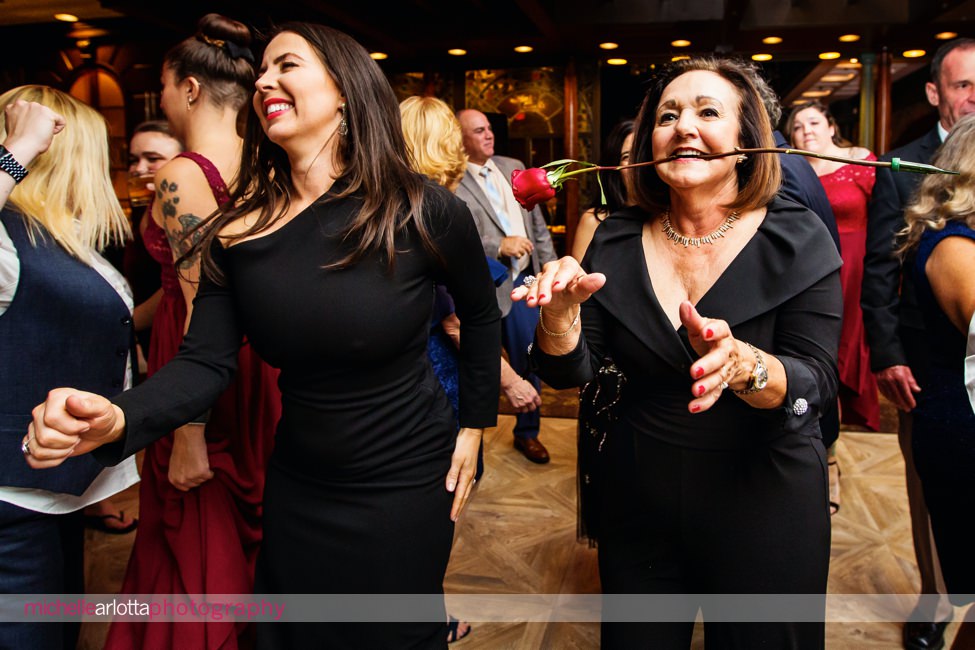 The manor NJ wedding reception woman with long stem rose in her mouth