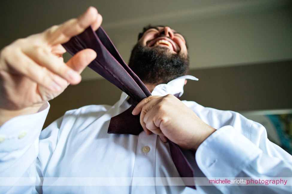 nj wedding Ryland Inn groom laughing while tying tie