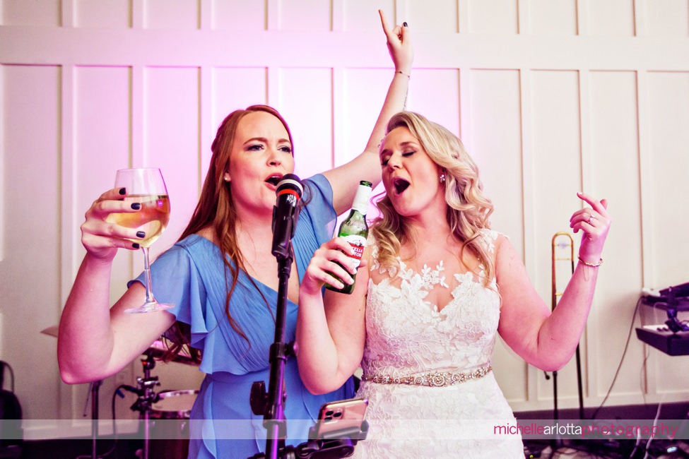 mid winter Ryland Inn coach house New Jersey wedding reception bride and bridesmaid singing on the microphone