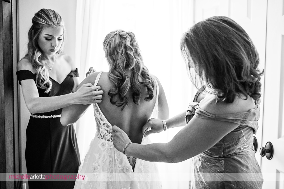 The Farmhouse wedding new jersey bride getting into dress with help of mother and sister