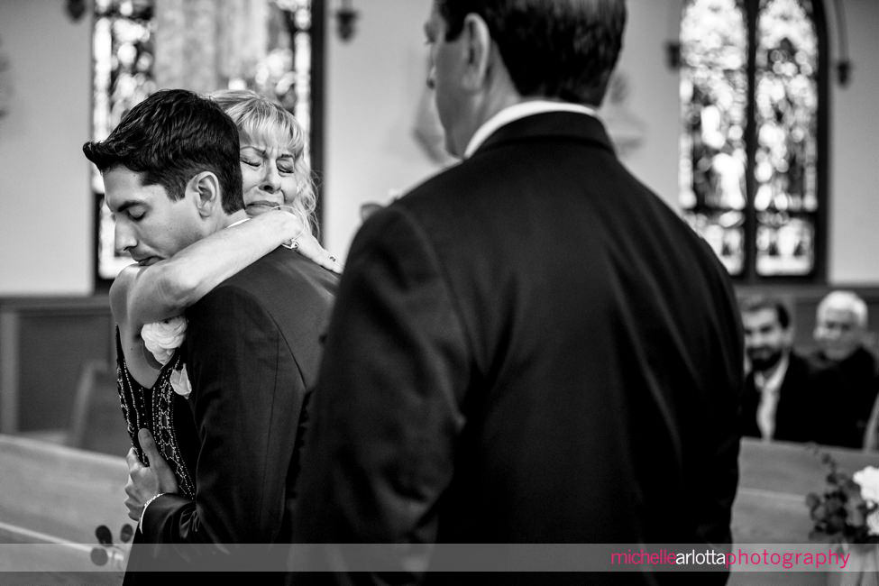 Backyard New Jersey wedding ceremony mom crying as she hugs son at altar