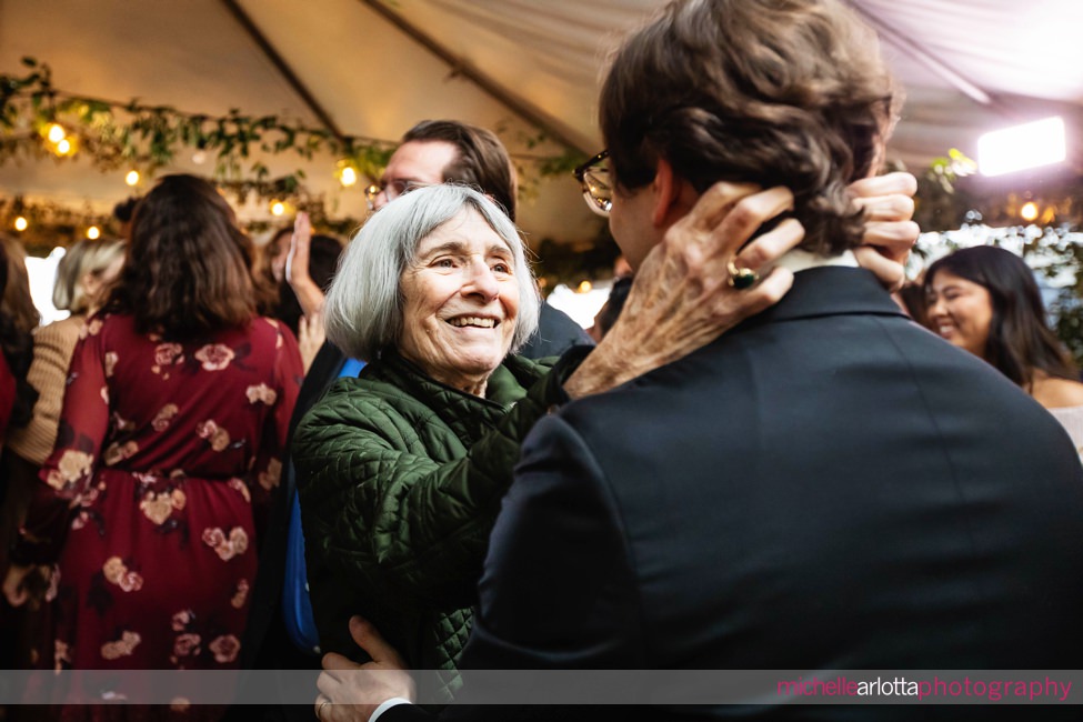 New Jersey backyard wedding tented reception grandmother grabs onto groom