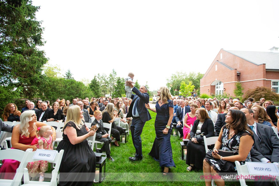 Park Avenue Club Florham park New Jersey outdoor wedding ceremony groom's father raising infant grandson up in the air like the lion king