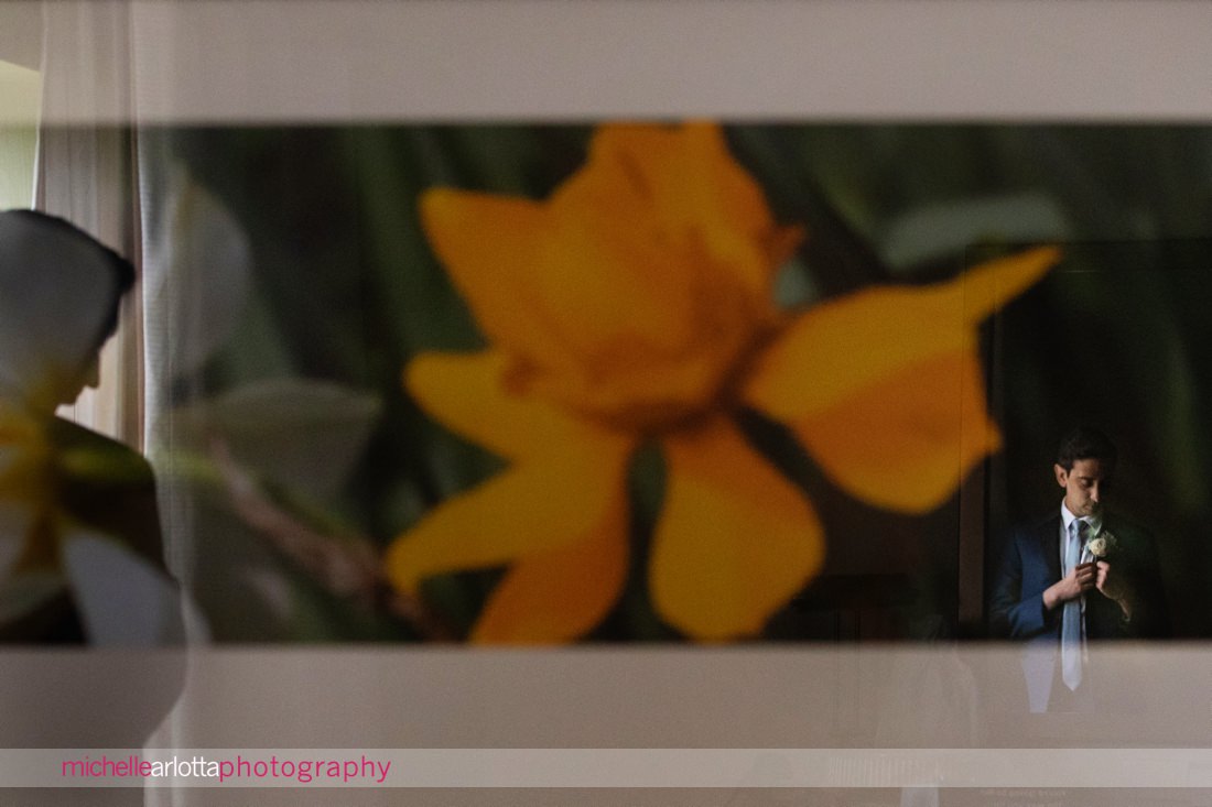 Phoenixville PA groom putting on boutonniere in reflection of flower painting