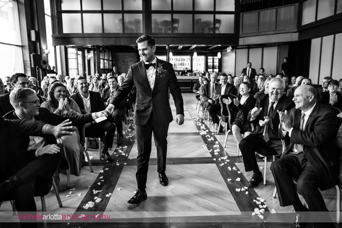 gallery at liberty prime jersey city indoor wedding ceremony groom fist bumping as he walks down the aisle 