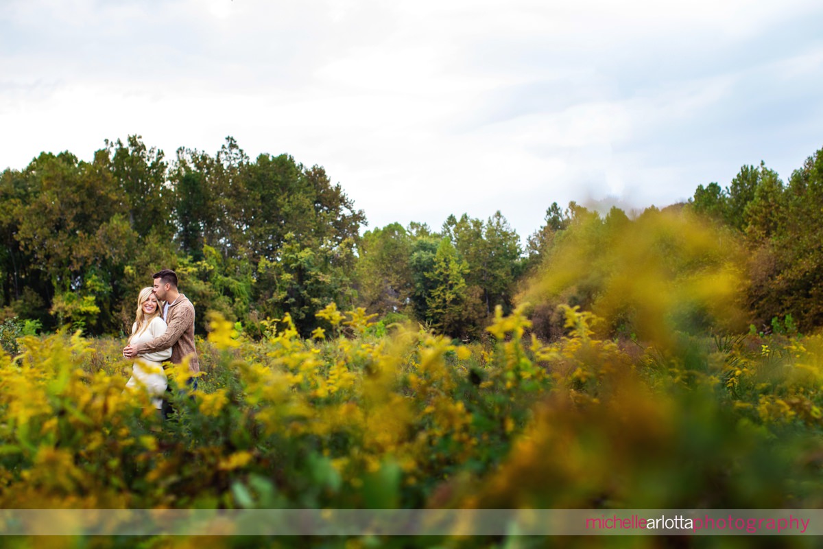 Frenchtown Fall mini engagement session couple embraces in a field of goldenrod in nj