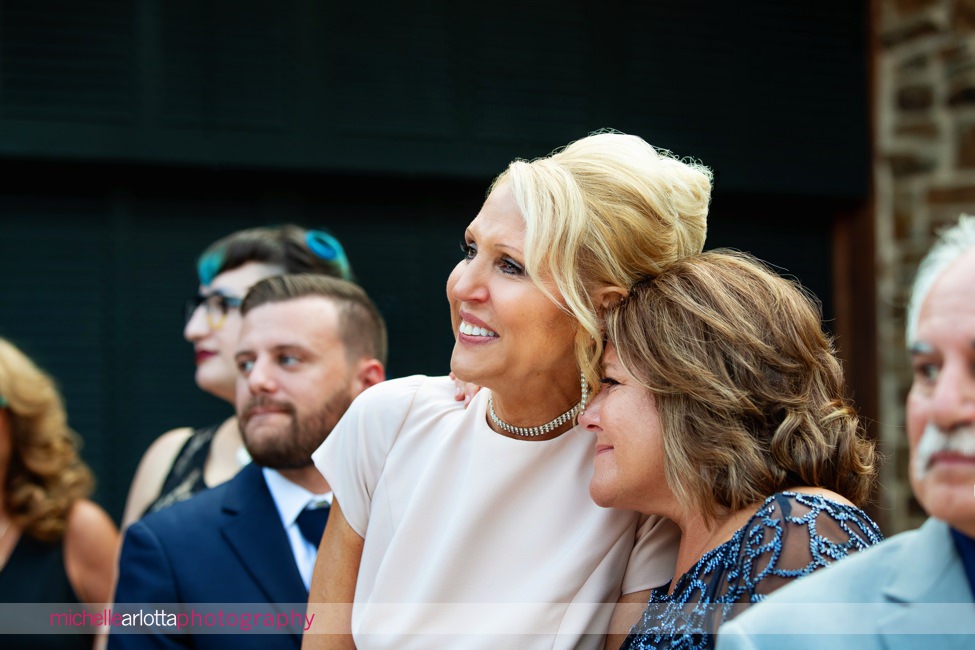 The Madison Riverside NJ outdoor wedding ceremony mother of the bride and mother of the groom sharing a moment as the bride walks down the aisle