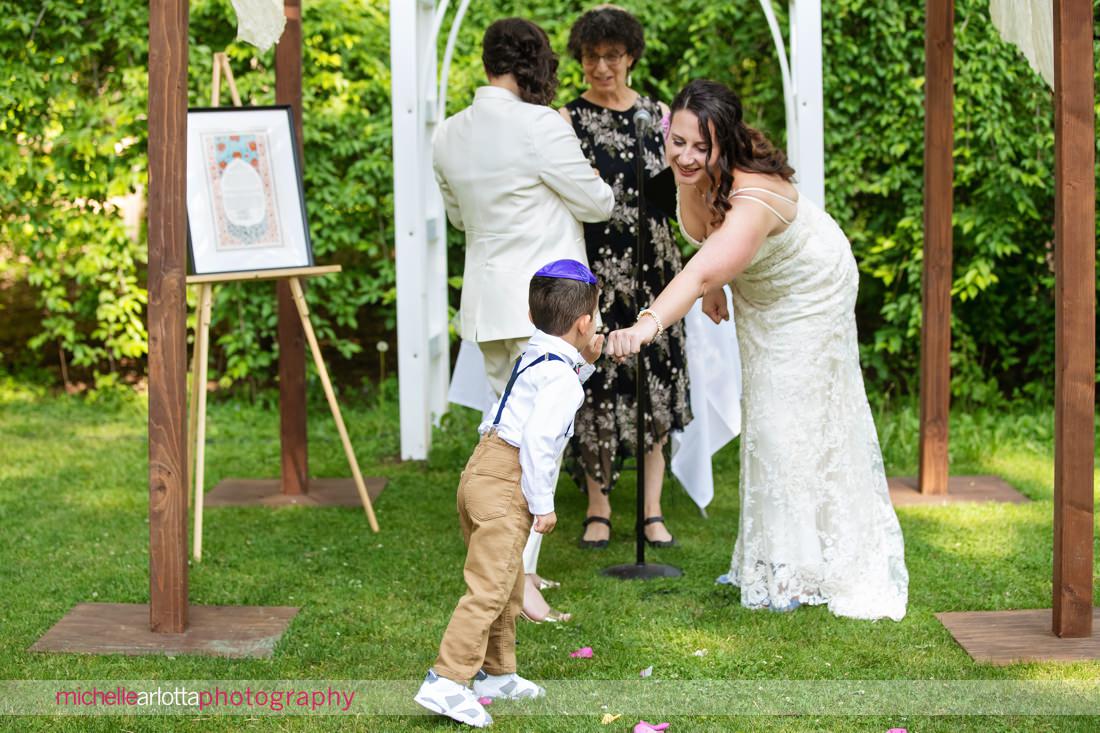 ring bearer fist bumps bride as he hands off rings during New Paltz NY wedding