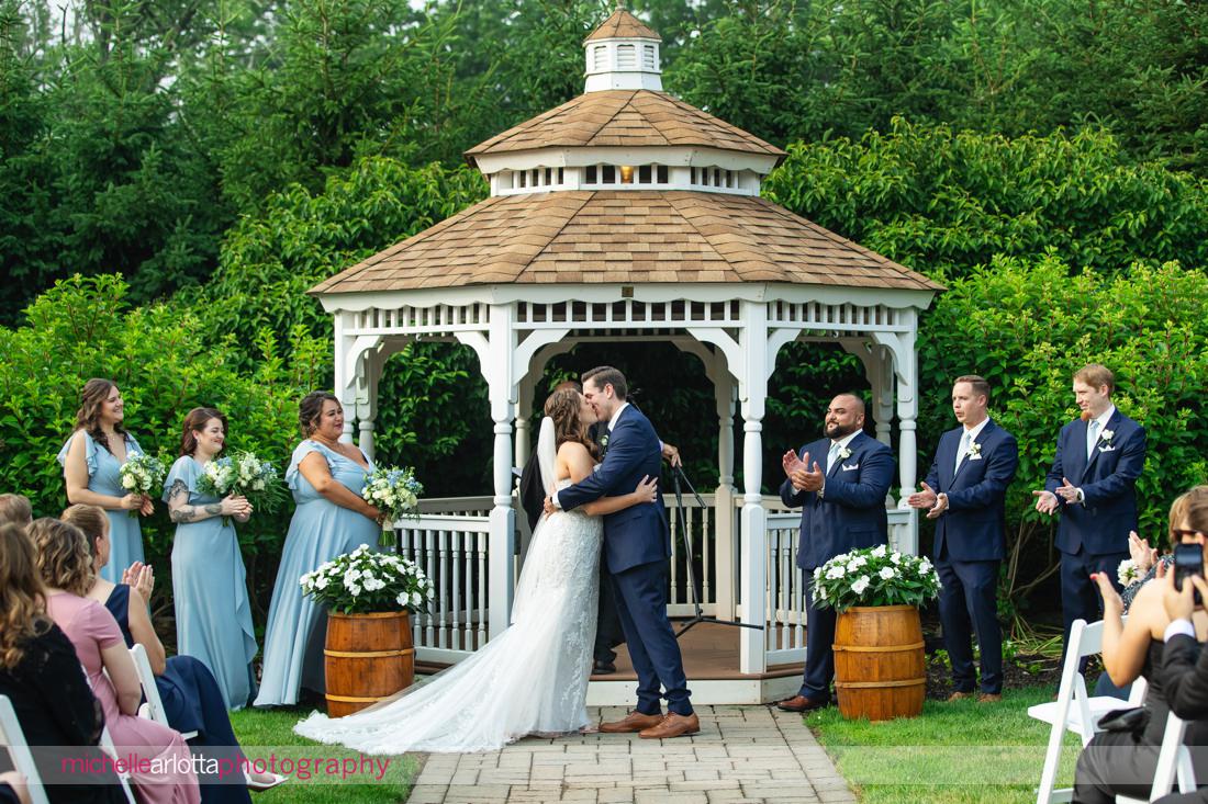 Outdoor ceremony at The Farmhouse NJ summer wedding bride and groom kiss