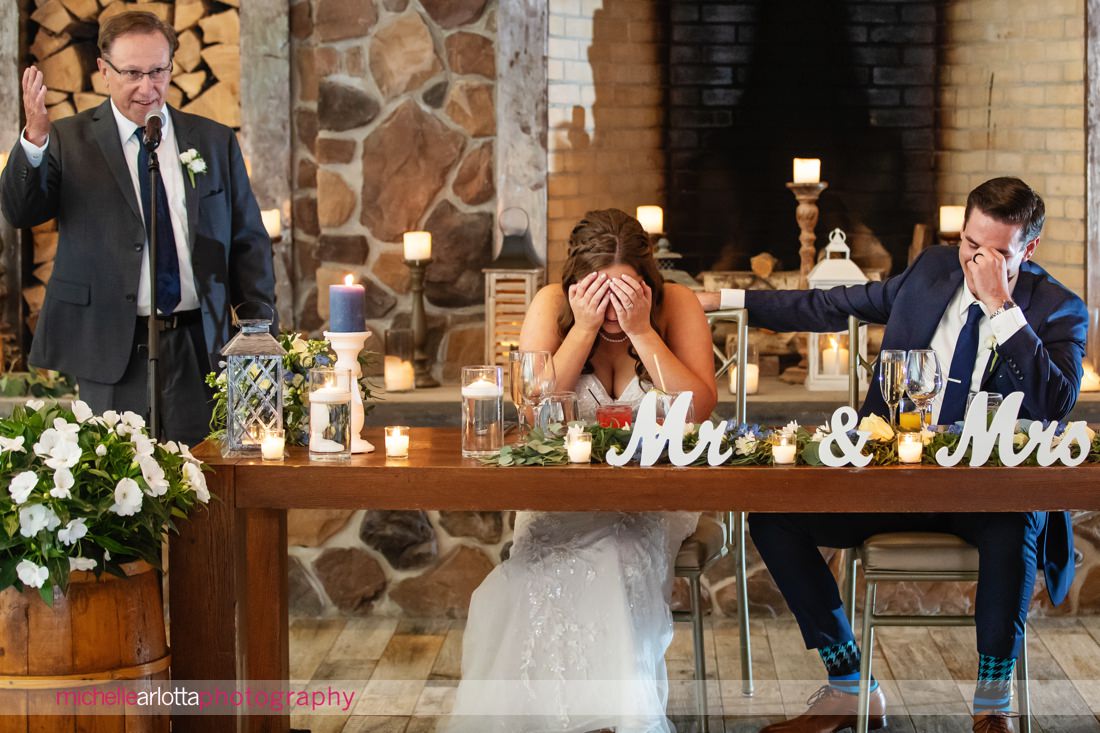 The Farmhouse NJ summer wedding reception bride and groom cover their faces during dad's toast
