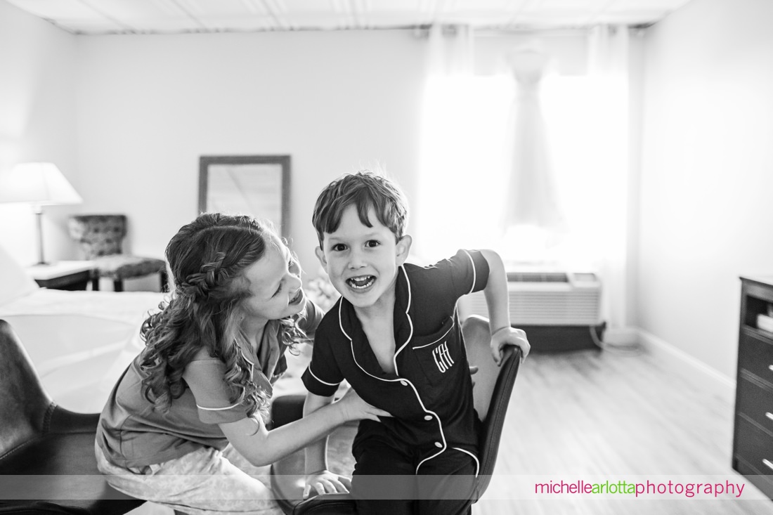 ring bearer and flower girl playing around while wedding dress hangs in the background at The Shore Club