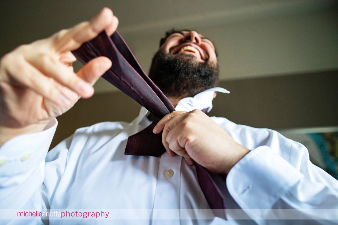 picture from a low angle of groom tying tie for Ryland inn nj wedding