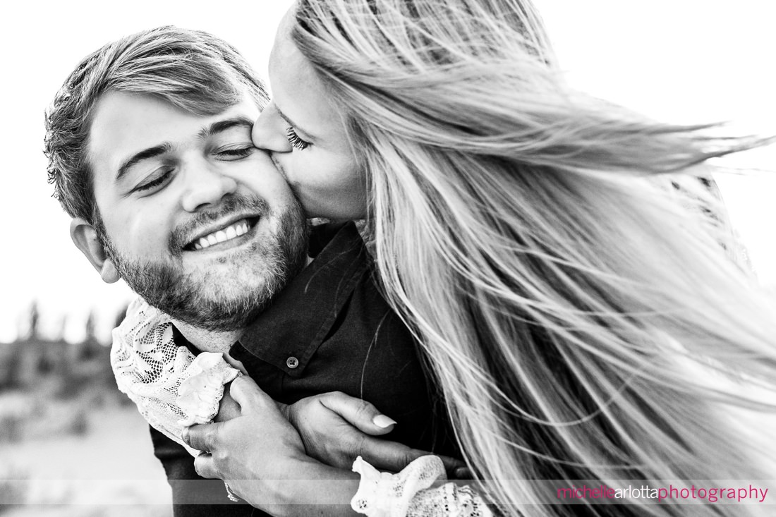 bride kissing groom on the cheek during Avalon nj beach engagement session