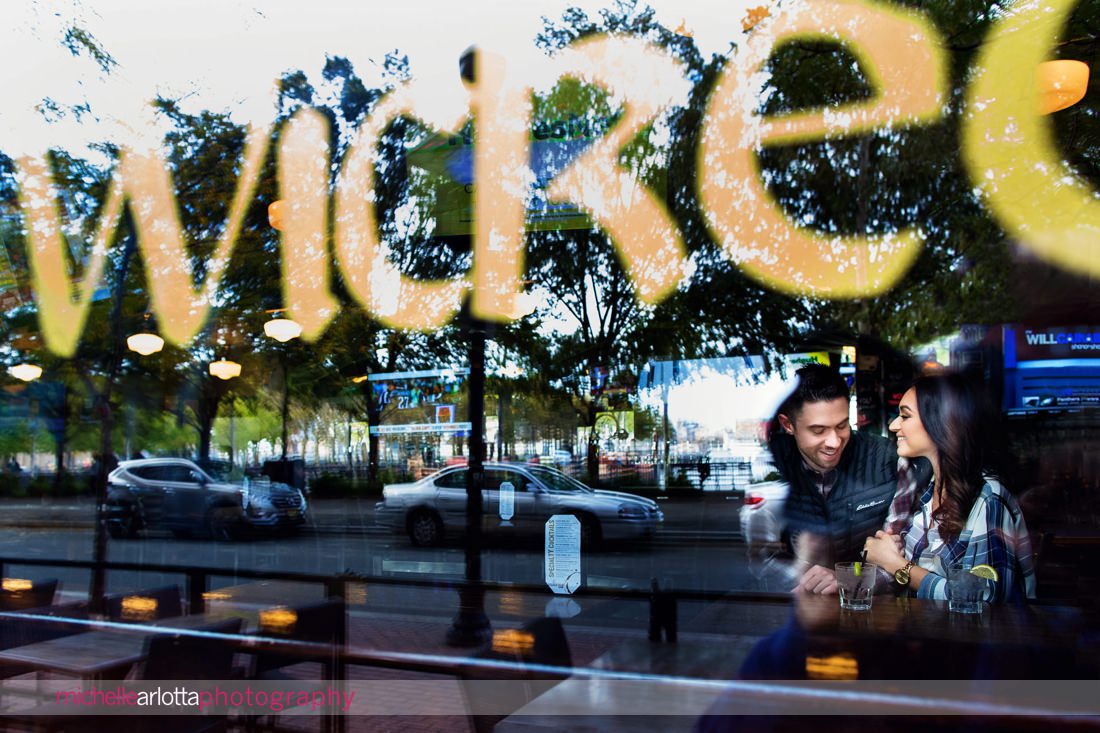 image shot from outside the window of a bar as bride and groom share a drink in Hoboken ny