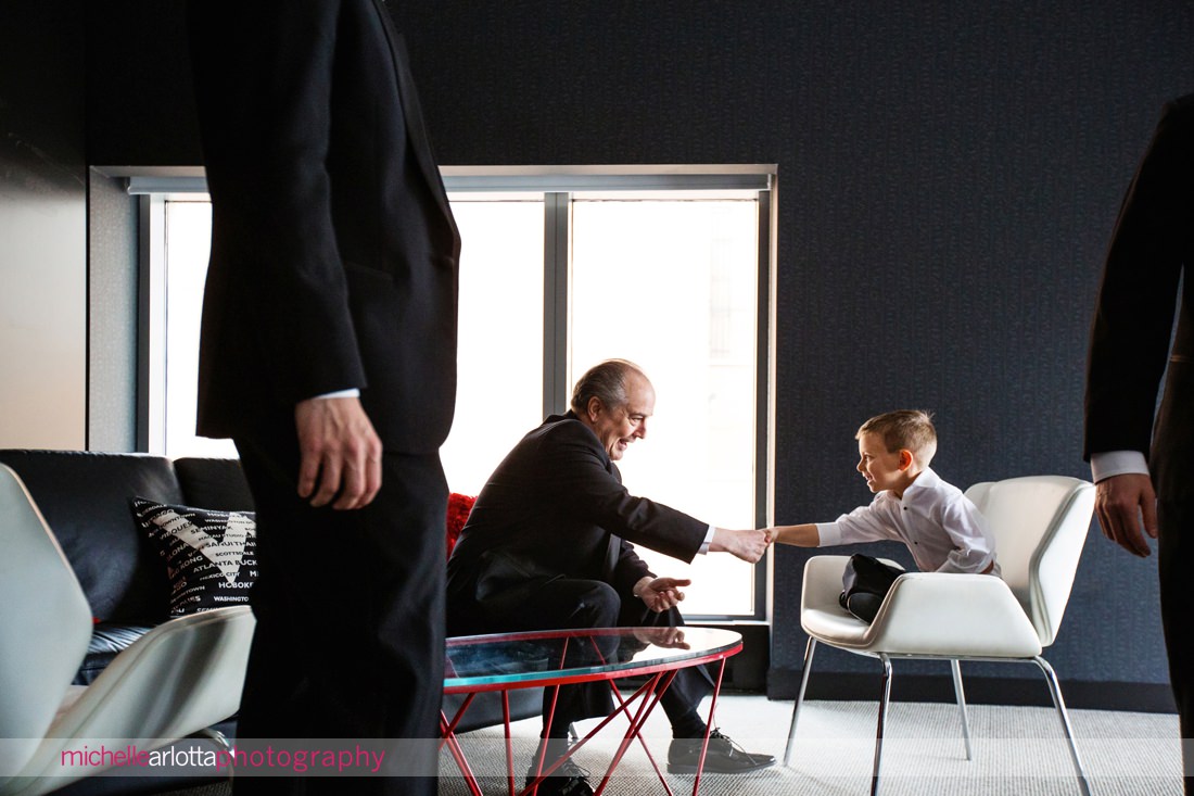 little boy and older man shake hands in the background of a groom prep