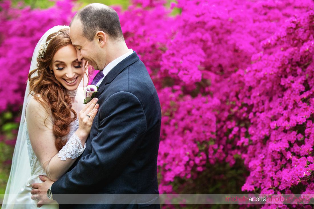 bride and groom in front of bright pink flowers at their skylands manor nj wedding 