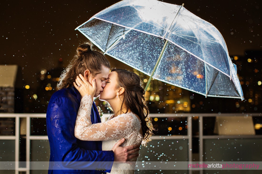 bride and groom kissing in the rain on the rooftop at night in NYC