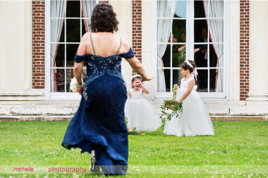 grandmother runs toward flower girl as she cries prior to walking down the aisle