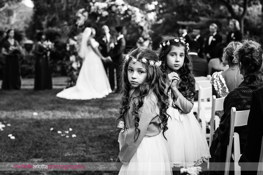two flower girls with flower crowns turn back to the camera during skylands manor nj wedding ceremony