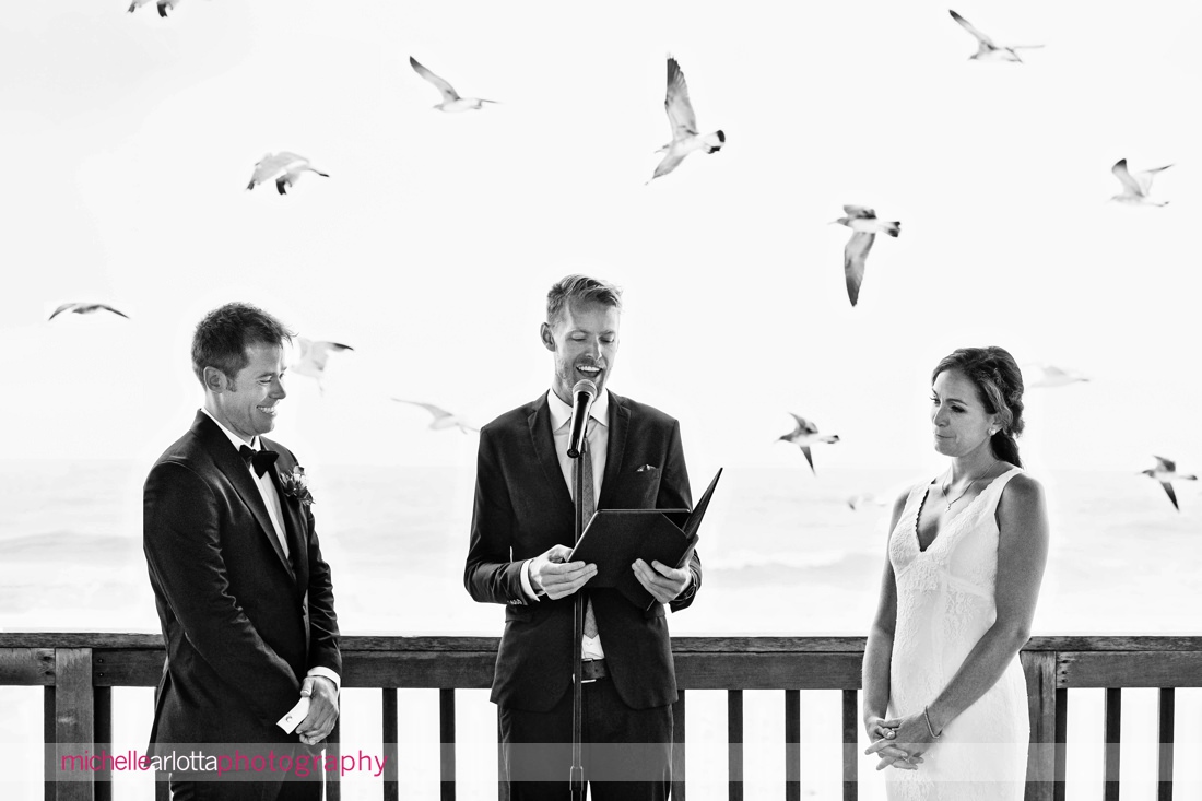 seagulls scatter behind couple during brant beach yacht club lbi outdoor wedding ceremony 