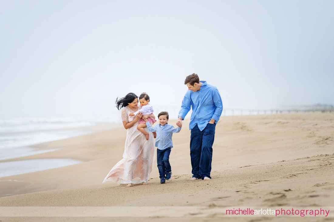 mother, father, son, daughter walk on beach during Asbury Park Beach NJ family portrait session